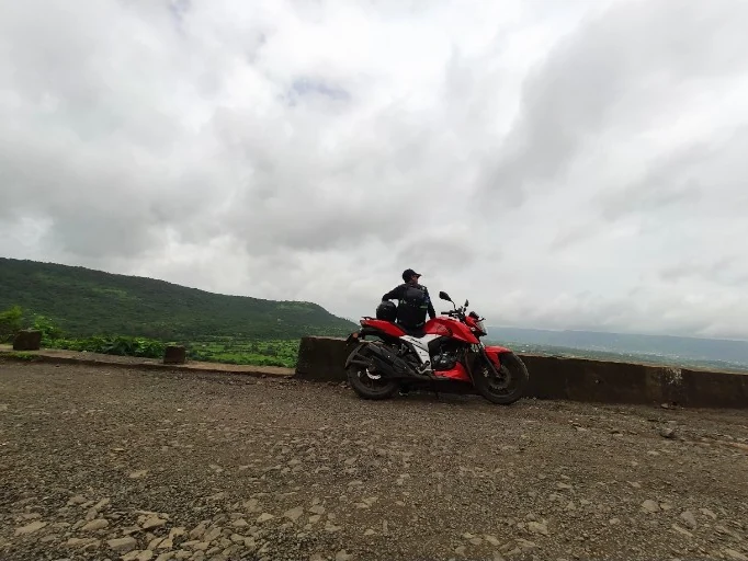Himanshu on a motorcycle surrounded by hills